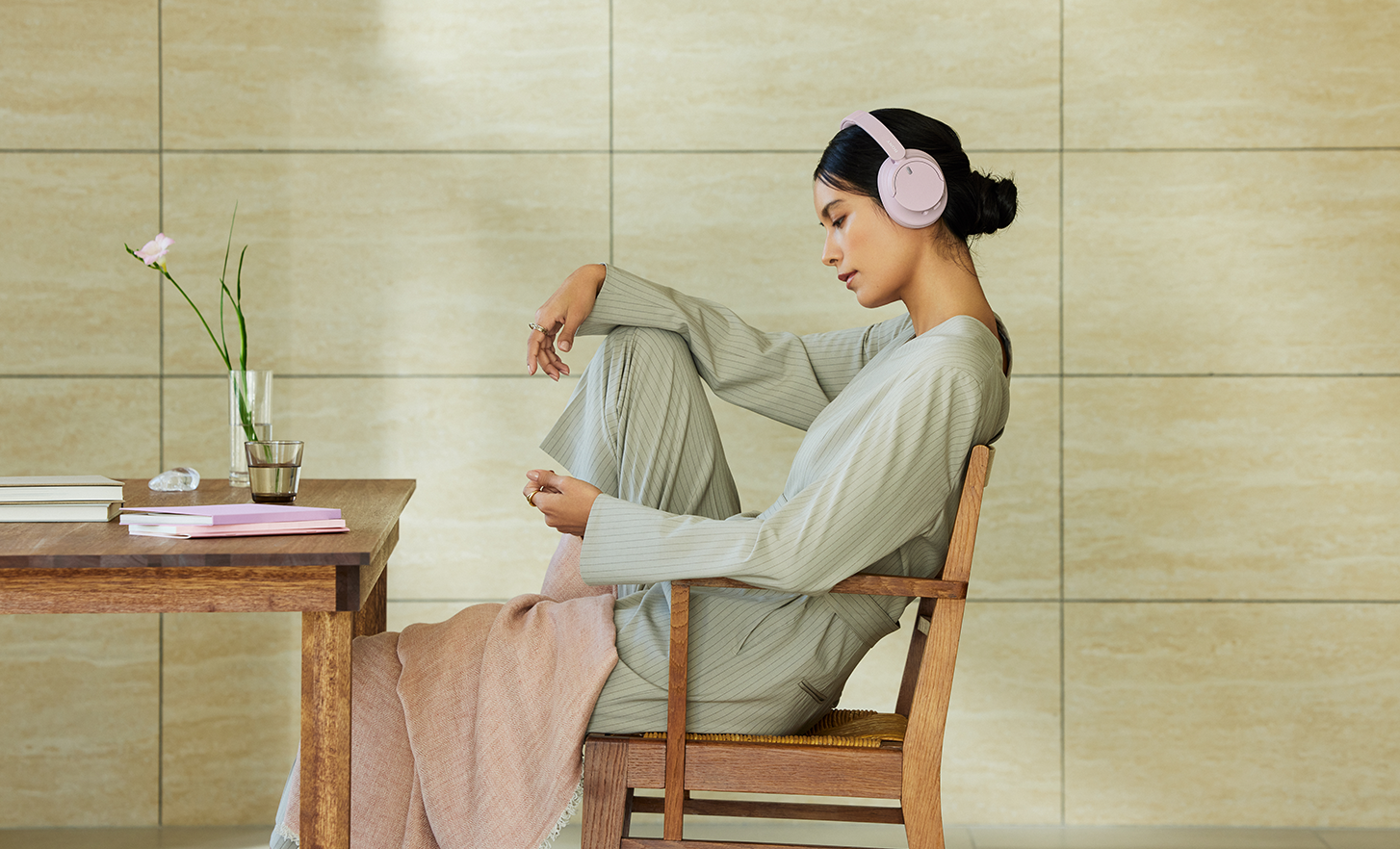 Person wearing a pair of pink Sony WH-CH720N headphones, relaxing in a minimalistic space.